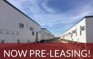 A row of rectangular modular buildings, making up a workforce housing camp. Text superimposed on the image says “Orla, Texas – Now Pre-Leasing!”