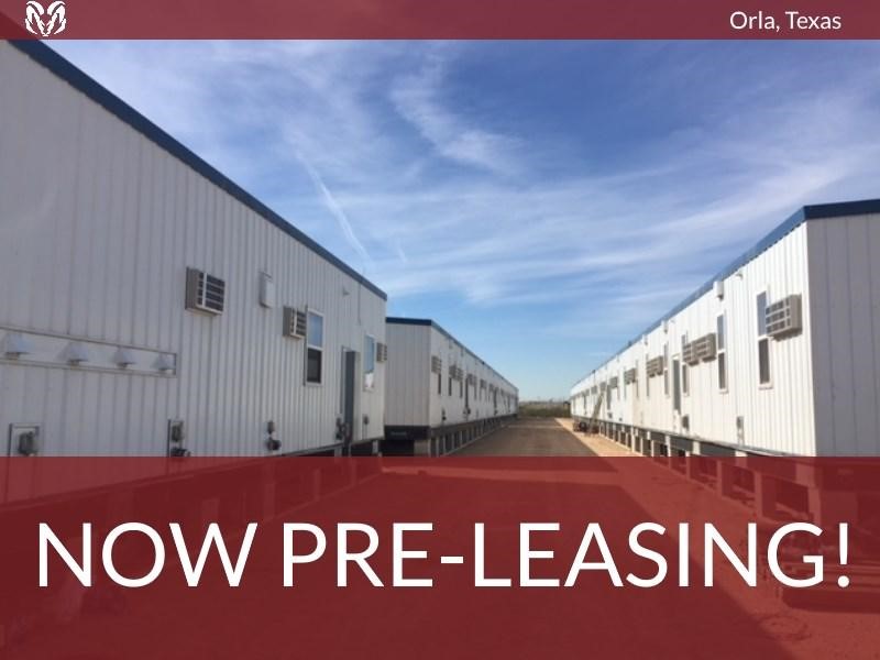 A row of rectangular modular buildings, making up a workforce housing camp. Text superimposed on the image says “Orla, Texas – Now Pre-Leasing!”